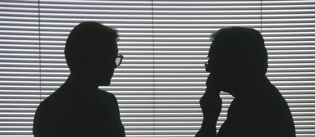 two people talking with blinds down in background